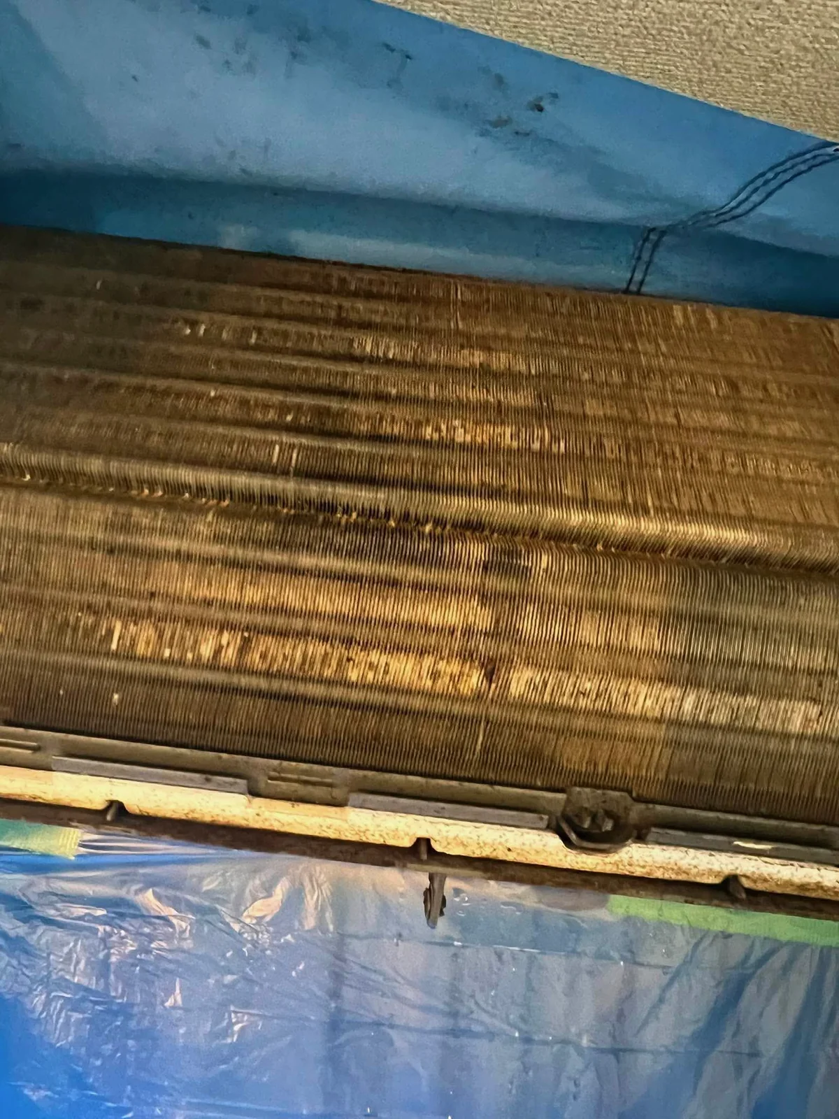茶色く汚れた熱交換器。養生シートを張って洗浄する直前